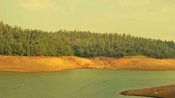 Günbatımında Pykara Gölü, Ooty, Tamilnadu 'nun güzel manzarası. Gökyüzü manzarası, su, gün batımı ve tekne yolculuğundan görülebilen yeşil çalılar. Güney Hindistan 'daki en iyi balayı yeri..