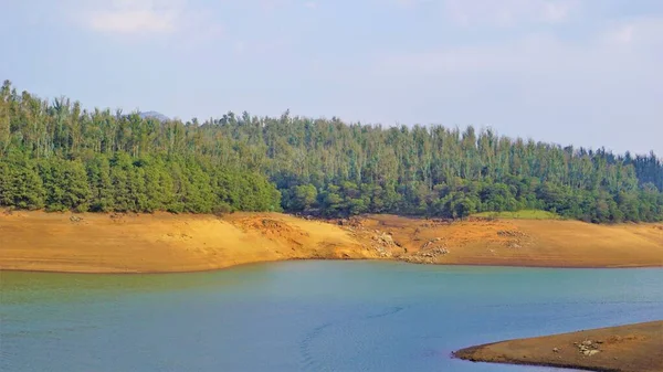 Günbatımında Pykara Gölü, Ooty, Tamilnadu 'nun güzel manzarası. Gökyüzü manzarası, su, gün batımı ve tekne yolculuğundan görülebilen yeşil çalılar. Güney Hindistan 'daki en iyi balayı yeri..