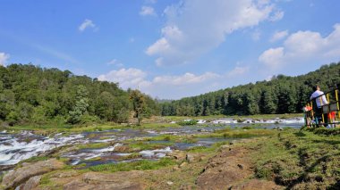 Ooty, Tamilnadu, Hindistan-30 Nisan 2022: Pykara Şelaleleri 'nde akan güzel nehir manzarasının tadını çıkaran turistler, Ooty. Güney Asya 'nın en iyi balayı turistik beldesi..