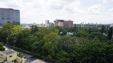 Bangalore,Karnataka,India-June 19 2022: View of Bangalore cityscape from terrace of Chancery Pavilion Hotel with busy road of Bangalore city. Stadium and skyscrapers such as Prestige UB City Concorde Block visible through green cover along with city 