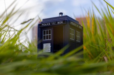 Doktor Who 'nun yeşil çimenlikteki TARDIS' i rolünde mavi polis kulübesi. Zaman makinesi. İnek nesnesi. 