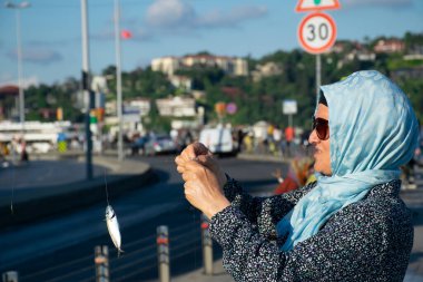 İstanbul, Türkiye - Haziran 2022: Taze tutulan uskumru balığı bir kadının eline takıldı