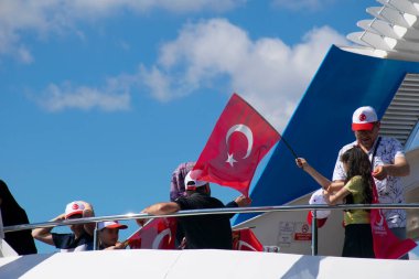 İstanbul, Türkiye - Temmuz 2022: Küçük kız bir gemide Türk bayrağı sallıyor. Genç bayan fotoğrafçı, gemide Türk bayrağı sallayan küçük bir kızın fotoğrafını çekiyor..