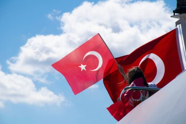 İstanbul, Türkiye - Temmuz 2022: Küçük kız bir gemide Türk bayrağı sallıyor. Genç bayan fotoğrafçı, gemide Türk bayrağı sallayan küçük bir kızın fotoğrafını çekiyor..