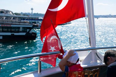Istanbul, Turkey - July 2022: Little Turkish boy waving turkish flag. Little Turkish boy holding the Turkish flag and those around him.