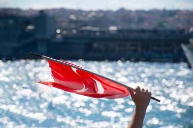 İstanbul, Türkiye - Temmuz 2022: Çocuk eliyle dalgalanan Türk bayrağı. Türk bayrağı ve İstanbul görüşü.