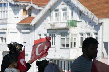 Istanbul, Turkey - July 2022: Woman holding the Turkish flag and those around him. People waving the turkish flag on the ship