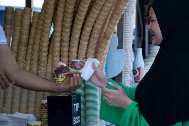 İstanbul, Türkiye - 24 Haziran 2022: Türk dondurma satıcısı şakaları ve müşteriler eğleniyor. Geleneksel Türk dondurması satışları.