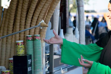 İstanbul, Türkiye - 24 Haziran 2022: Türk dondurma satıcısı şakaları ve müşteriler eğleniyor. Geleneksel Türk dondurması satışları.