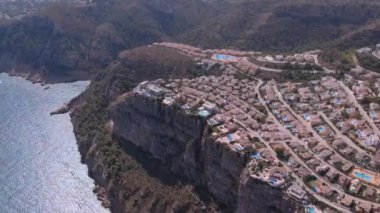 Okyanus kıyısındaki bir kayalıktaki lüks evlerin en üst görüntüsü. Tepelerin tepesindeki modern villalar. Okyanus ve uçurum dokusu.