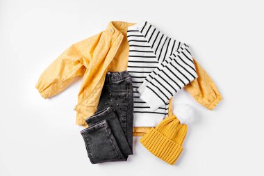 Sarı ceket, kot pantolon ve beyaz arka planda kazak. Sonbahar için çocuk kıyafetleri. Moda çocuk kıyafeti..