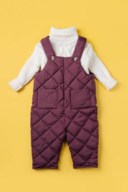 Warm pants and white sweater  on yellow background. Set of baby clothes for winter. Fashion kids outfit.	