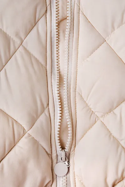 ジッパーでベージュのパフジャケットの質感をクローズアップ キルト布の背景 — ストック写真