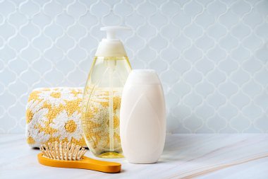 Sabun ya da saç fırçası ve gri arka planda havlu ile şampuan şişesi. Bebek banyo aksesuarları. Doğal güzellik ürünü konsepti.