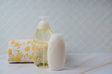 Sabun ya da şampuan şişesi ve gri arka planda havlu. Banyo aksesuarları