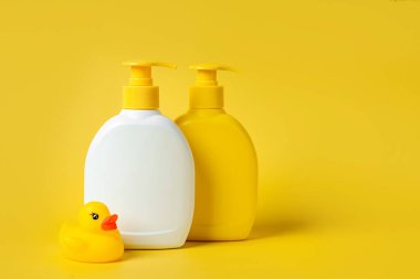 Sarı arka planda şirin ördekli sabun ya da şampuan şişeleri. Bebek banyo aksesuarları.