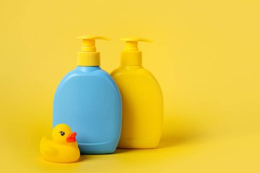 Sarı arka planda şirin ördekli sabun ya da şampuan şişeleri. Bebek banyo aksesuarları.