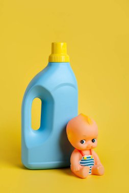 Sarı arka planda mavi bir şişede çocuk kıyafetleri için deterjan. Boş şişe ambalajı tasarla.