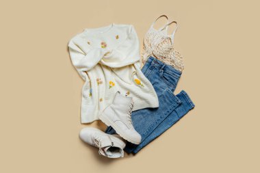 Bej arka planda kot pantolon ve botları olan şirin bir kazak. Şık sonbahar ya da bahar kıyafetleri. Moda konsepti. Düz yatış, üst görünüm.