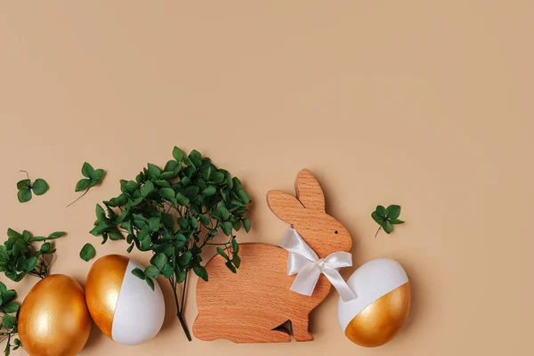 Kelinci Paskah Dan Telur Emas Dengan Bunga Hijau Latar Beige Stok Gambar