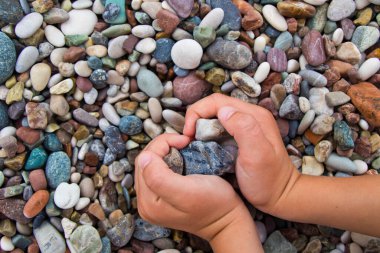 Antalya 'da kumsalda kalp şeklinde bir sürü taş tutan bir çocuk.