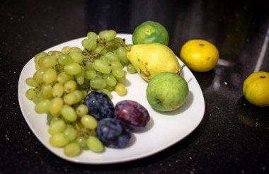 Yeşil üzümlü kırmızı erik. Tabakta yeşil elma.