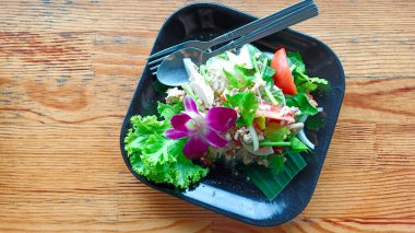 Siyah kare seramik tabakta ahşap zemine yerleştirilmiş vermicelli salatası.