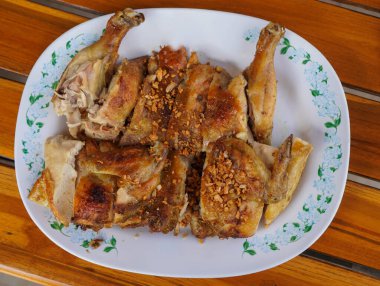 Üst manzaralı ızgara tavuk, beyaz plastik bir tabakta, ahşap bir masa arkasına, yiyeceğe, hayvana yerleştirilmiş.