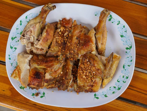 Üst manzaralı ızgara tavuk, beyaz plastik bir tabakta, ahşap bir masa arkasına, yiyeceğe, hayvana yerleştirilmiş.