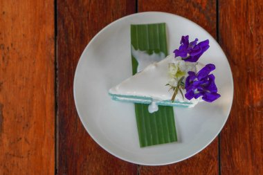 Beyaz seramik tabakta yeşil muz yaprağı üzerinde Anchan Hindistan cevizli keki, ahşap zemin zemin zemin üzerinde, yemek, tatlı, kopyalama alanı