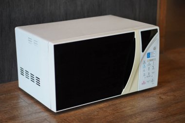 Ahşap zeminde eski beyaz ve krem mikrodalga fırın, gri duvar arkaplanı, teknoloji, nesne, dekor, kopyalama alanı                             