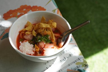top view yentafo large noodles, tom yum in a white ceramic cup, on the table background, blur grass green background, food, thaifood, copy space                               