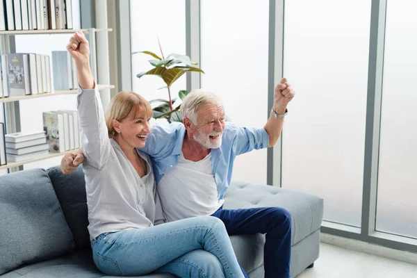 Yaşlı bir aile çifti modern oturma odasında birlikte oturuyor. Mutlu ve romantik bir gülümsemeyle..