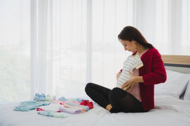 Hamile kadın günlük kıyafet planında ve onun ya da çocuklarının kıyafetlerini modern yatak odasındaki gelecekleri için hazırla..