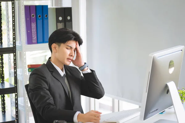 Business Asian man manager in formal suit overworked feeling pain from his disease symptom problem in modern office workplace.
