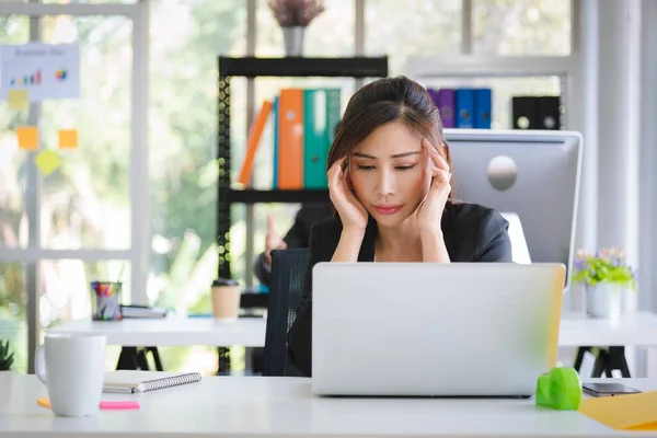 Business Asian woman in formal suit overworked and feeling stress and depress from work with unhappy emotion in modern office workplace.