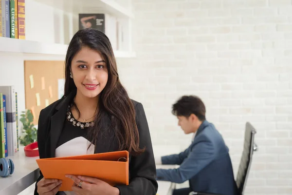 Portrait of business woman in formal outfit working in modern workplace with her colleagues in background.