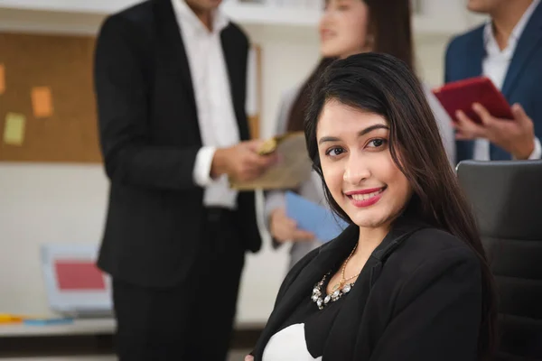 Portrait of business woman in formal outfit working in modern workplace with her colleagues in background.