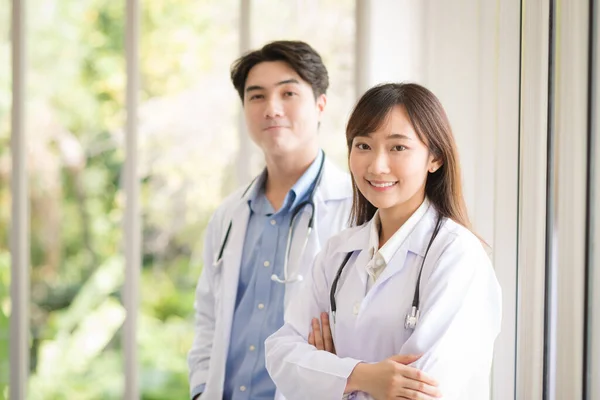 Group of Asian doctors team portrait in white lab coat professional uniform standing with colleagues in background.