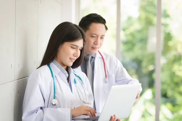 Group of Asian doctors team portrait in white lab coat professional uniform standing with colleagues in background.