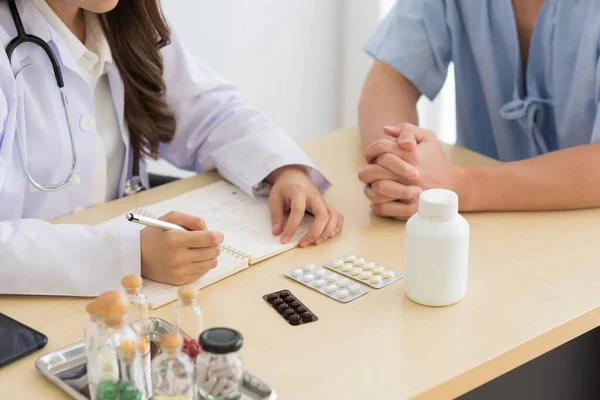 Asian doctor in professional work uniform discuss and explain symptoms to her patient.