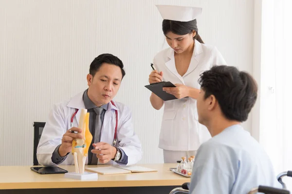 Asian doctor in professional work uniform discuss and explain symptoms to his patient.