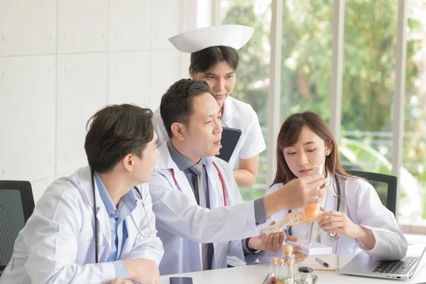 Group of Asian doctor in working uniform meeting and discuss with other colleagues in modern office clinic room.