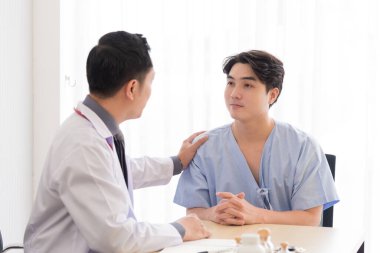 Profesyonel iş üniformalı Asyalı doktor hastasını mutluluk ve umutla tartışıyor ve neşelendiriyor..