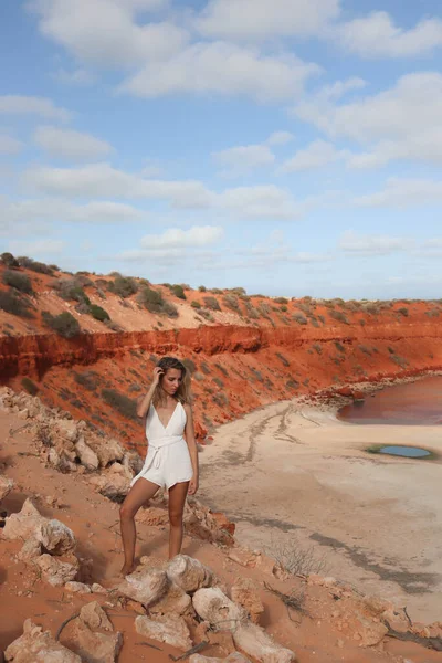 Woman in white dress looking at the cliff with red sandy beach on Australia — Stockfoto