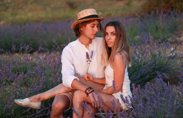 Portrait of happy young couple in love sitting in a field of lavender — стоковое фото