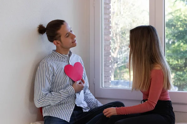 Casal Apaixonado Sentado Uma Janela Com Coração Vermelho Como Sinal — Fotografia de Stock