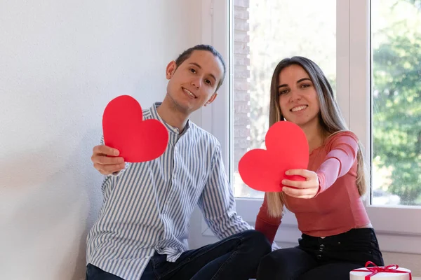 Мужчина и женщина учат и держат два красных сердца — стоковое фото