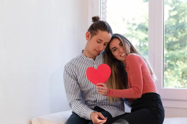Paar verliefd knuffelen elkaar terwijl het houden van een rood hart — Stockfoto