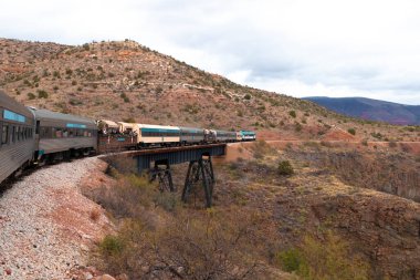 Arka planda çölsel manzara ile hareket eden tren.
